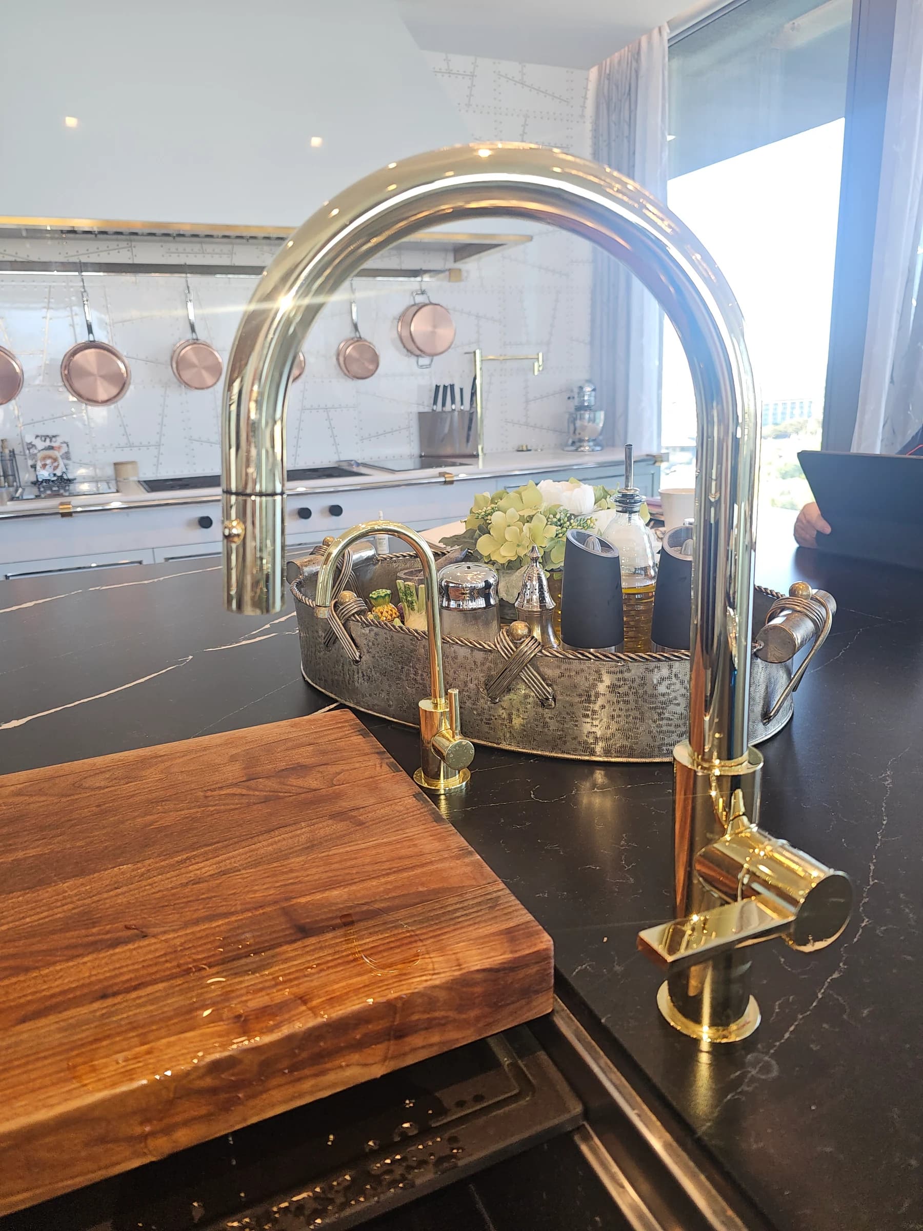 Brass faucet on a black marble waterfall island.