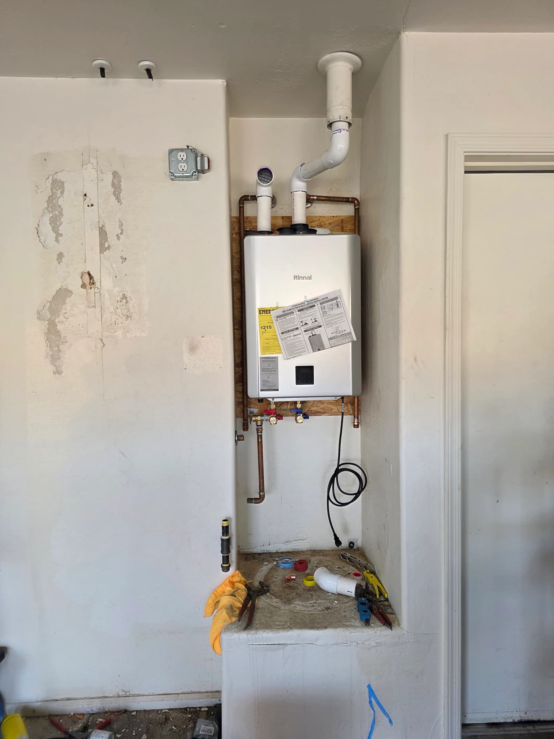 After: Two tanks and an expansion tank out, one wall-mounted Rinnai tankless in — and a garage back.