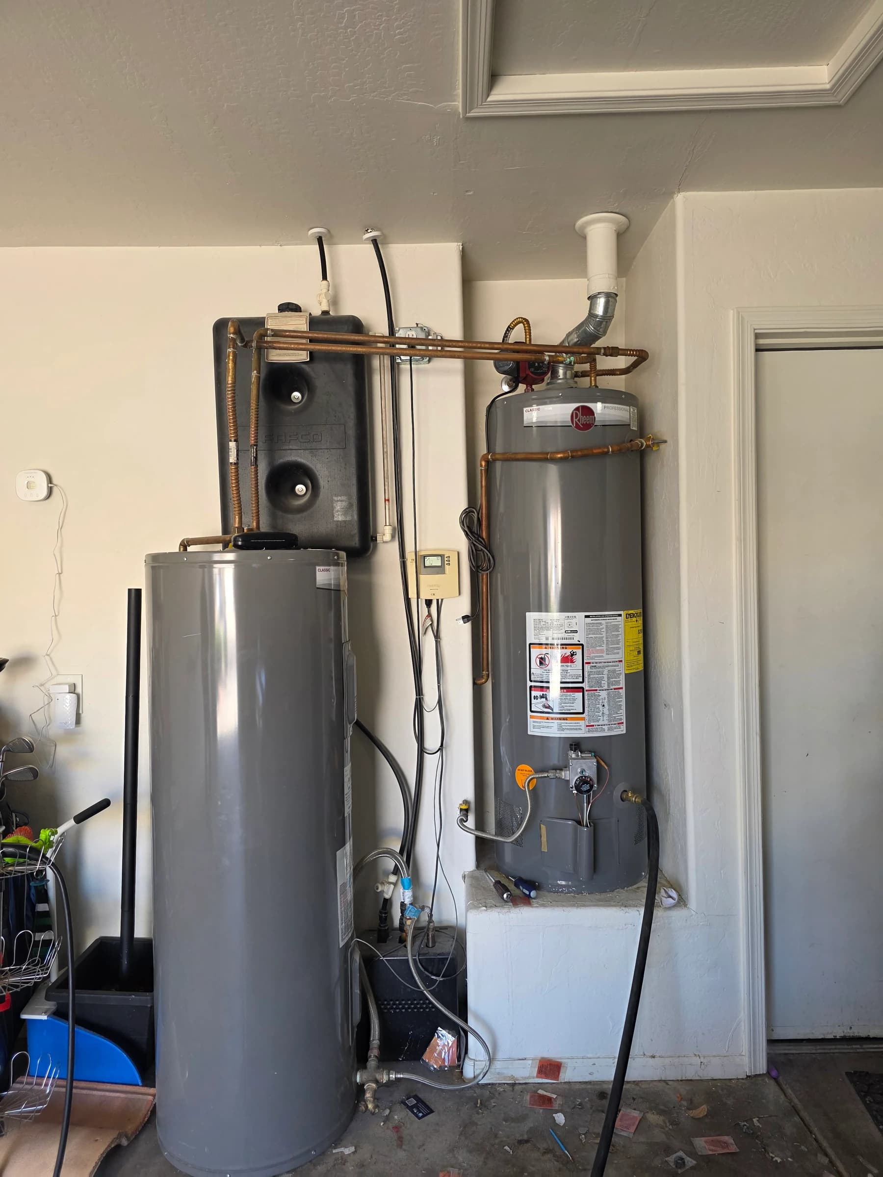 Before: Two tanks and an expansion tank out, one wall-mounted Rinnai tankless in — and a garage back.