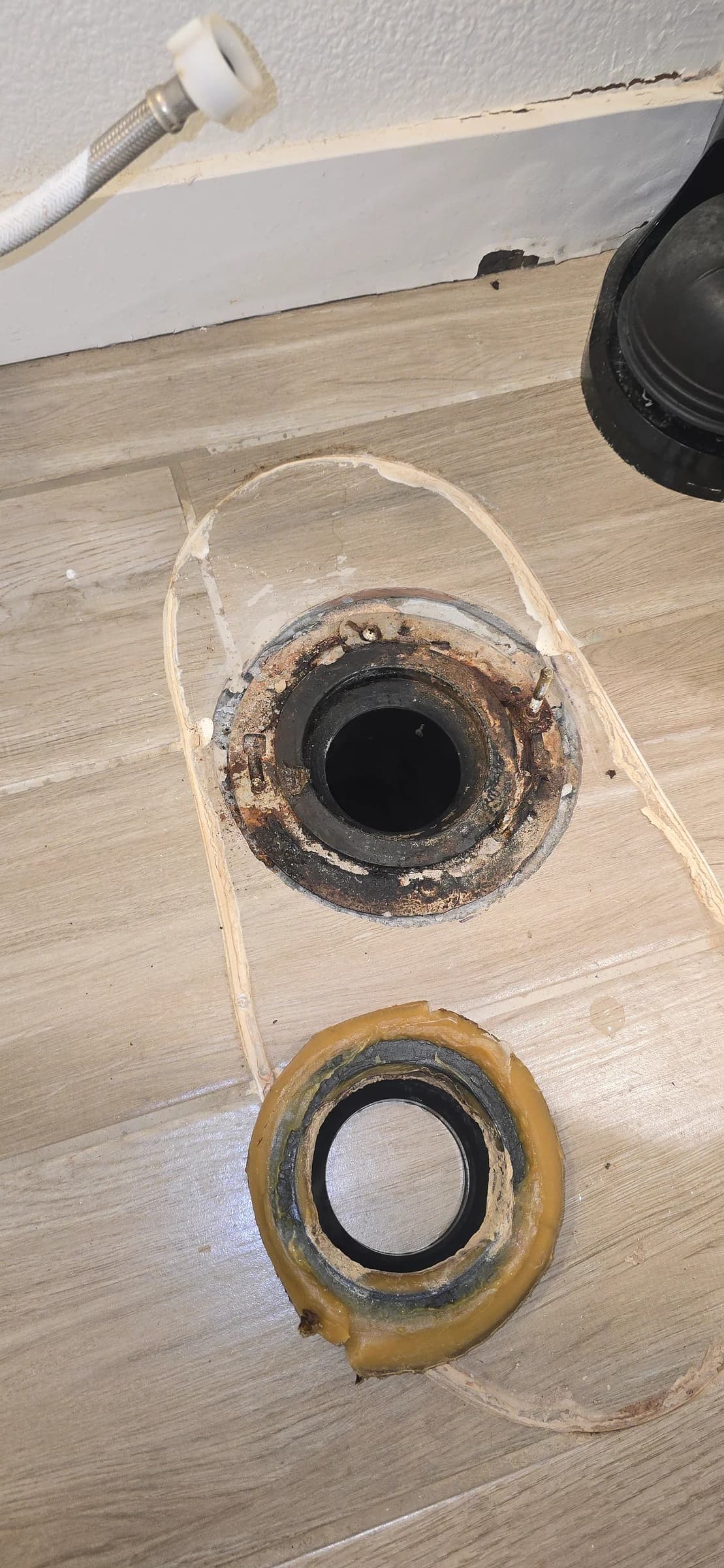 Before: Corroded flange and a spent wax ring, reset and sealed. $159 — and far cheaper than the flooring it was about to ruin.