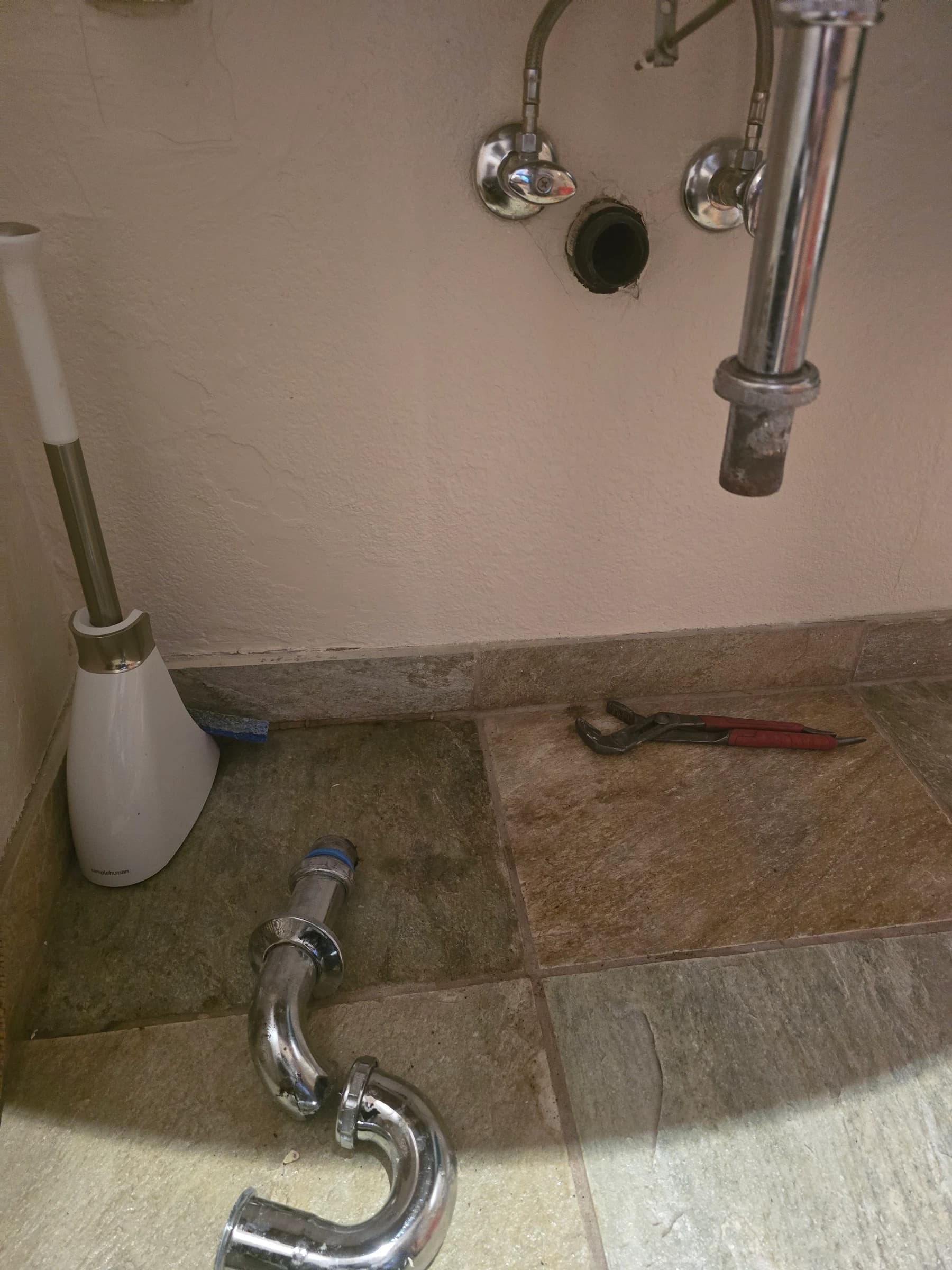 Chrome P-trap and supply lines on a finished vanity.