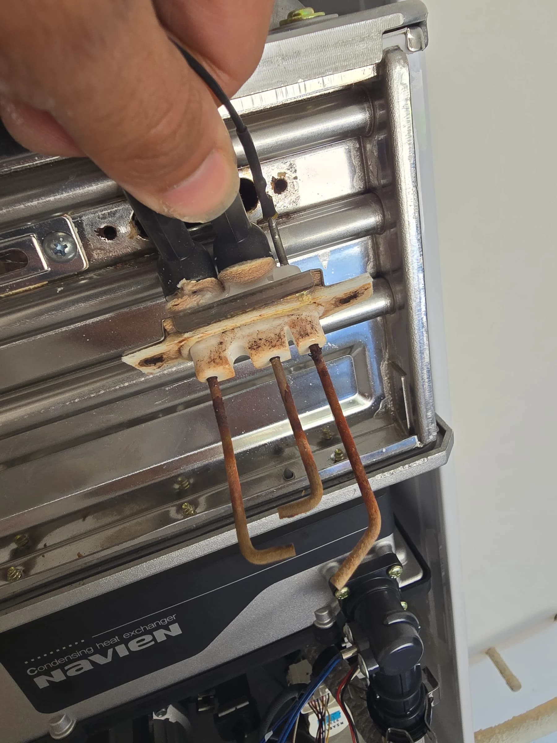 A Navien tankless heat exchanger removed and caked in white mineral scale
